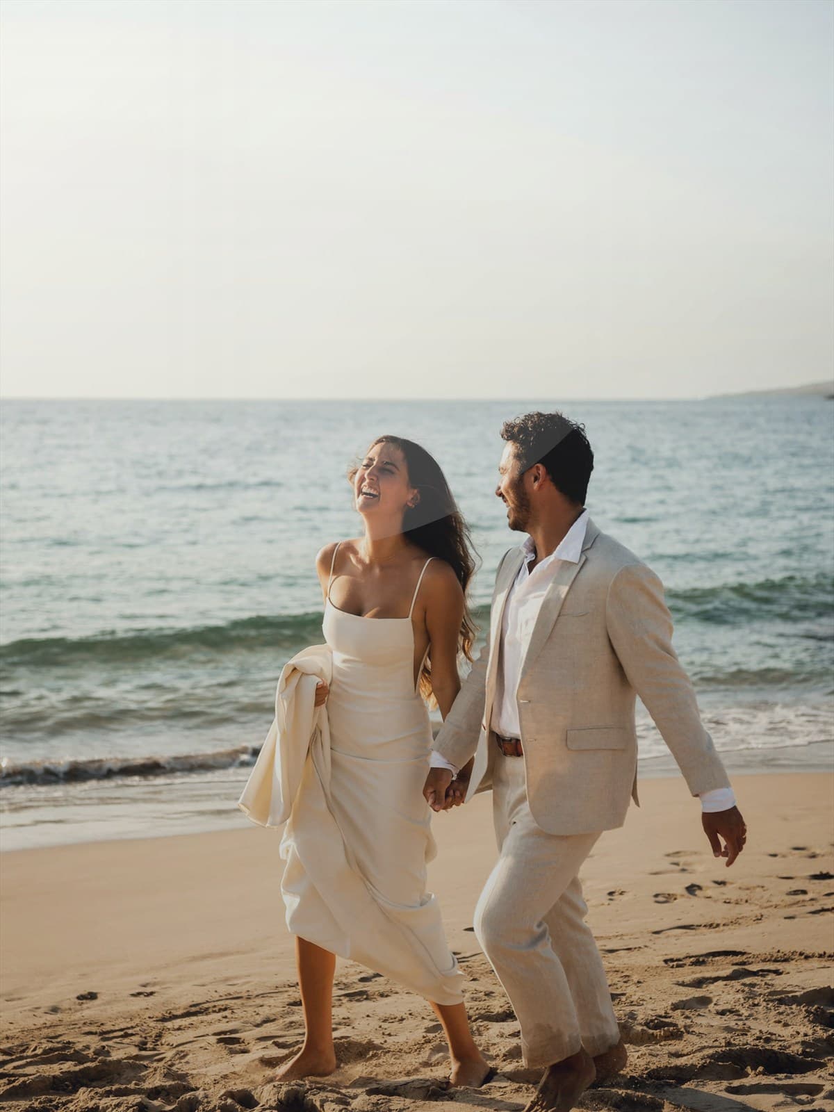 Couple walking on the beach at sunset.