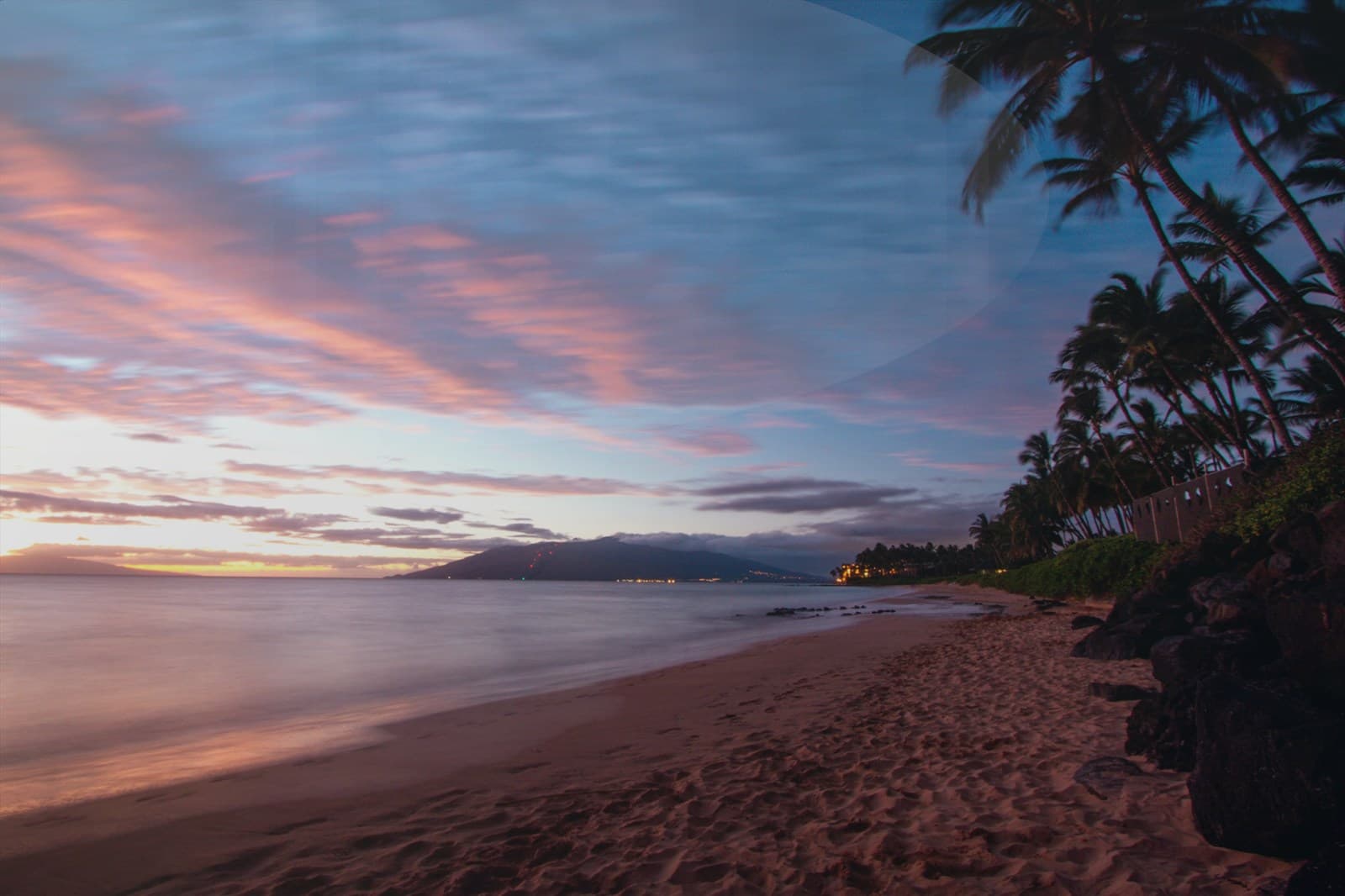 Family walking together on the beach at sunset.