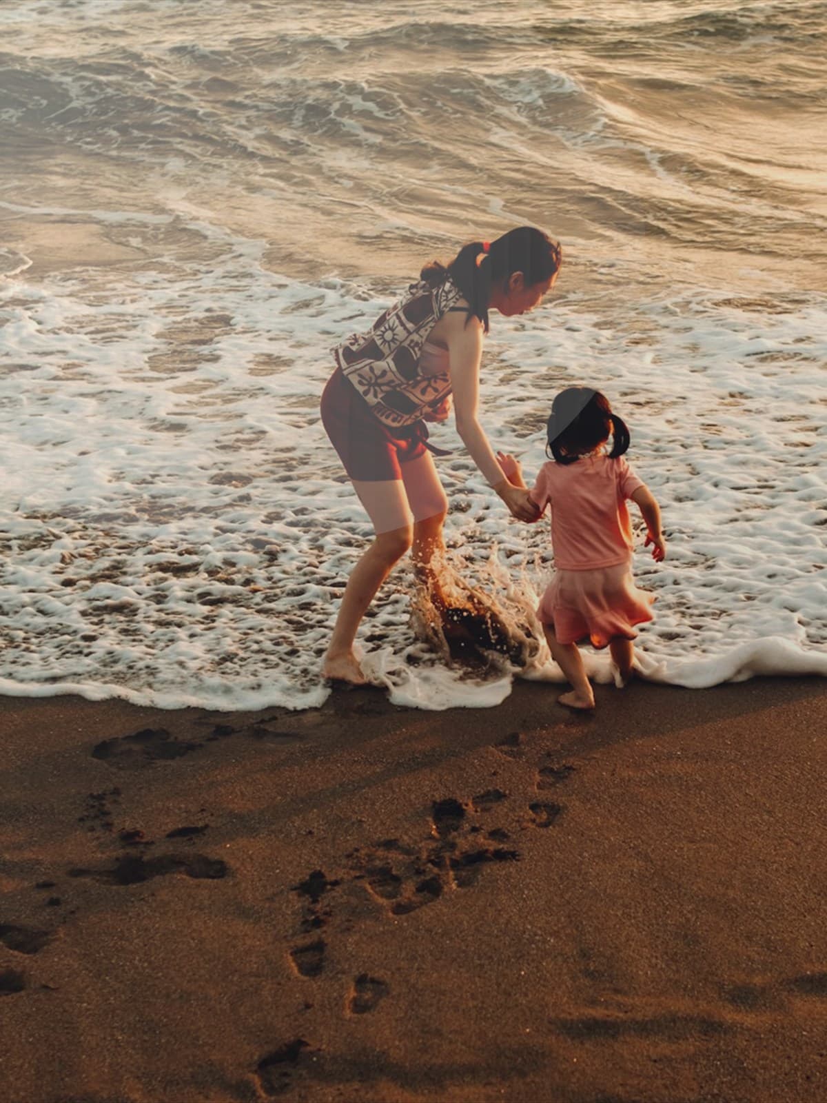 Pregnant couple standing together on the beach during sunset.