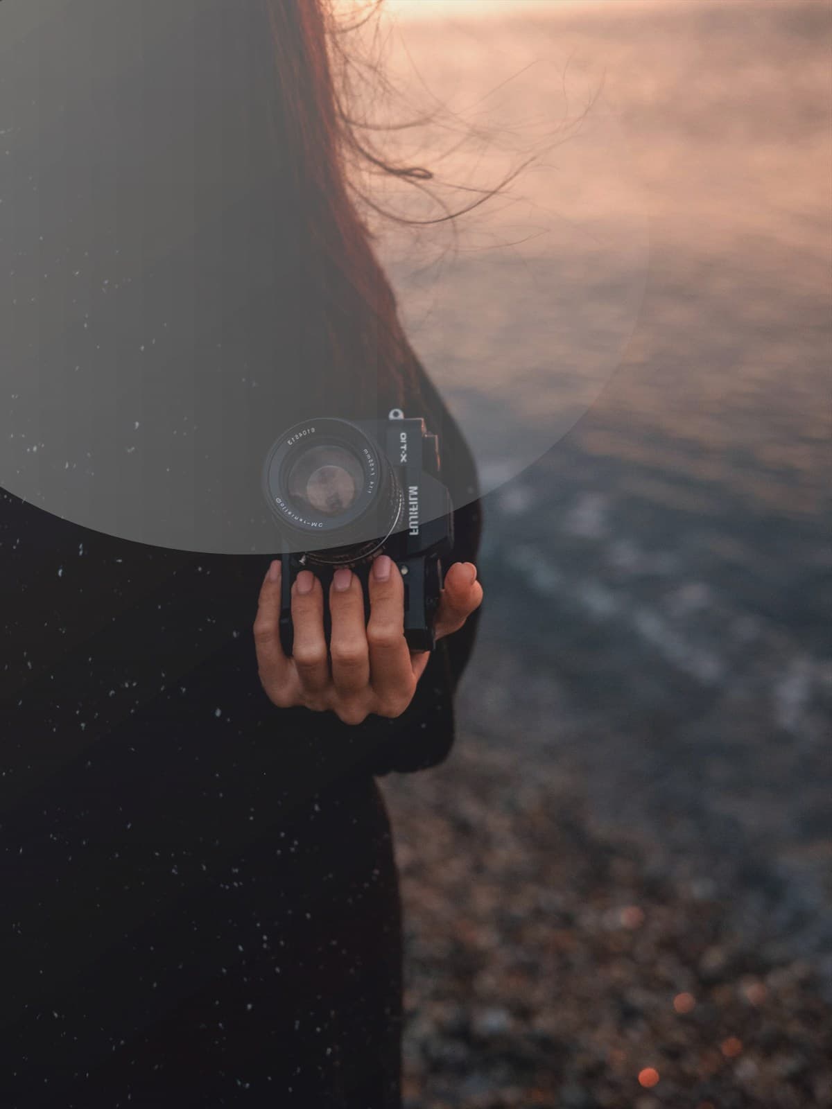 Partner embracing a pregnant woman on the beach at sunset.